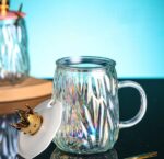 ⁦مج زجاج متعرج 450 ملي بغطاء تاج ومعلقة استانليس ستيل جولد للمشروبات الباردة والساخنة بيد⁩ - الصورة ⁦5⁩